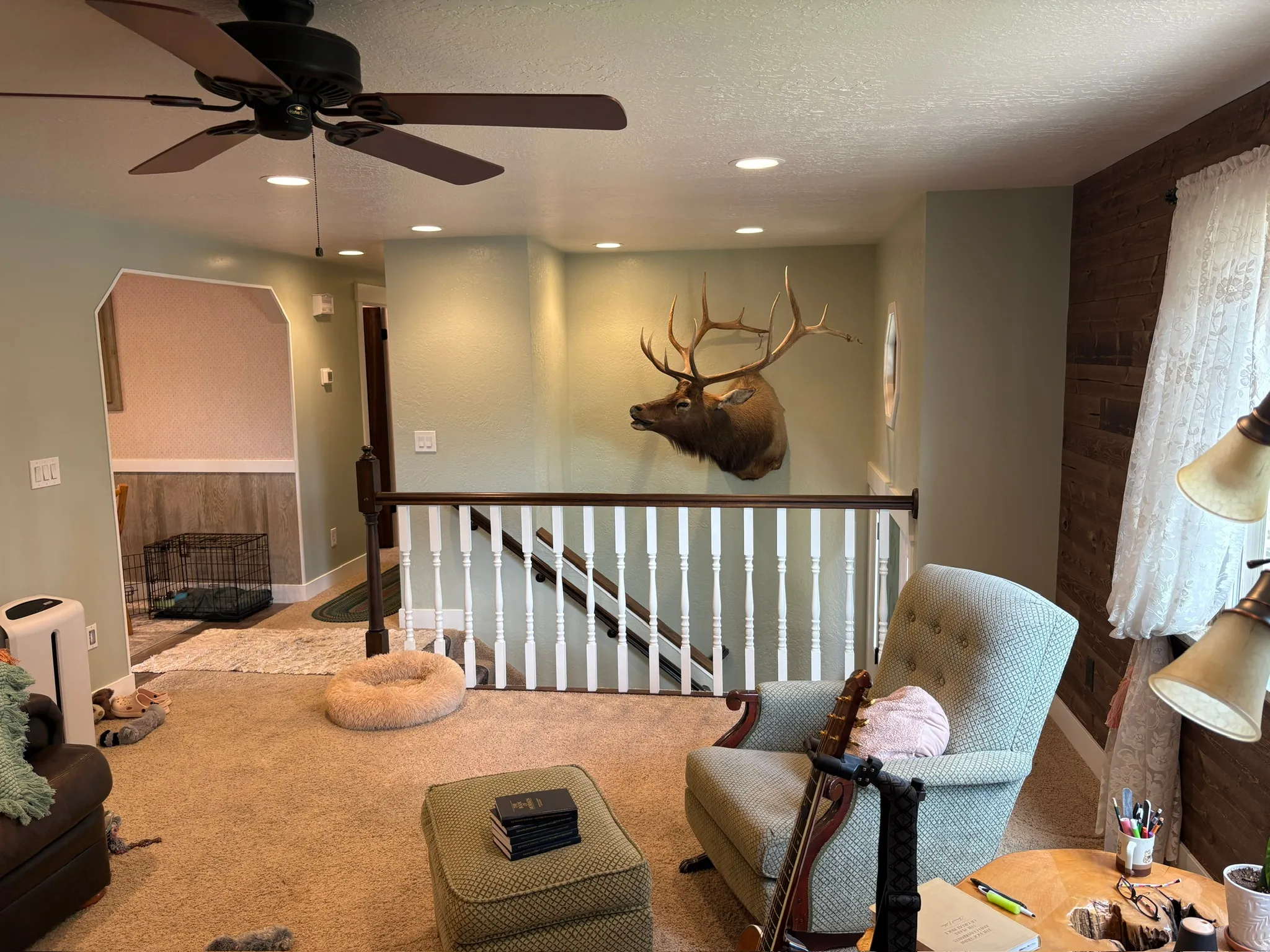 Carpeted living area featuring a ceiling fan with integrated lighting, recessed ceiling lights, and a decorative wood accent wall