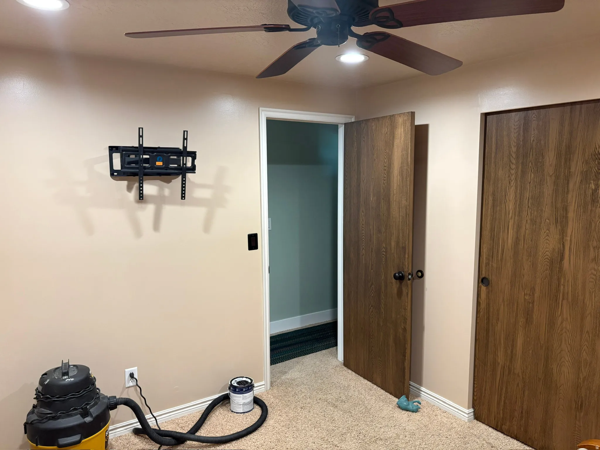 Carpeted interior space featuring a ceiling fan with integrated lighting, recessed ceiling lighting, and two wood-finish closet doors