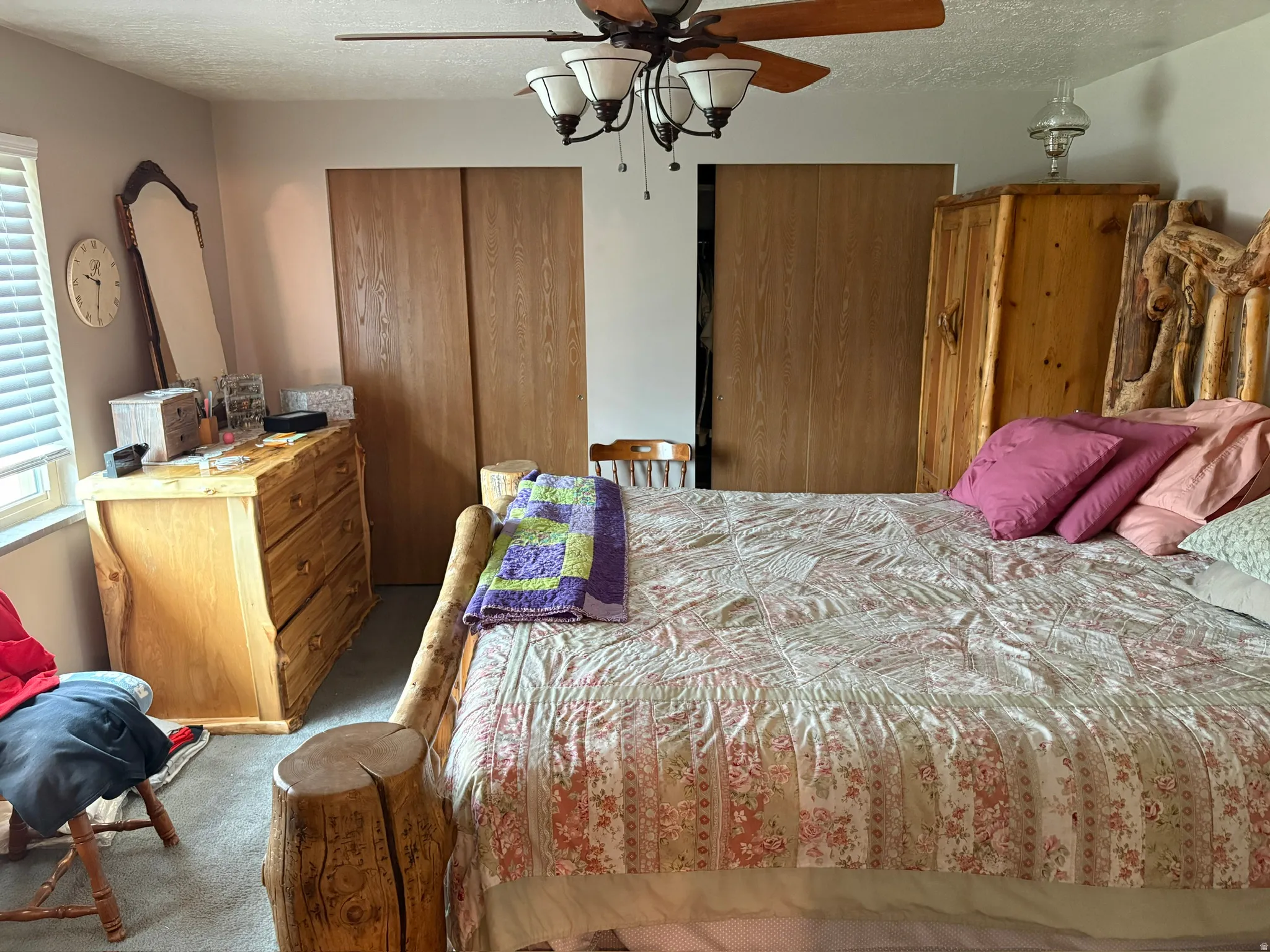 Carpeted room featuring a ceiling fan with integrated lighting, wood-finish sliding closet doors, and a window with blinds