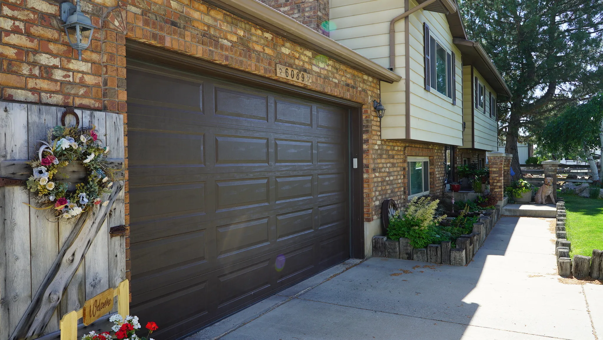 Brick facade with a paneled garage door and an adjacent paved driveway