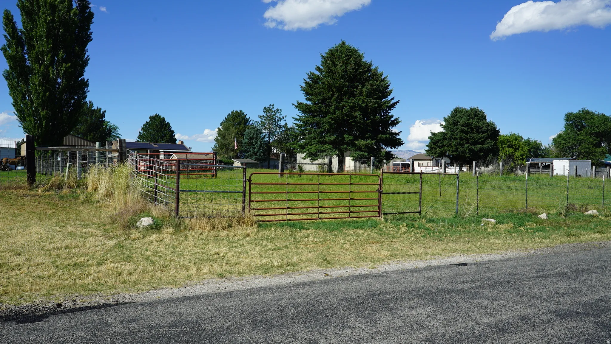 Expansive open lot featuring a metal gate entrance and perimeter fencing