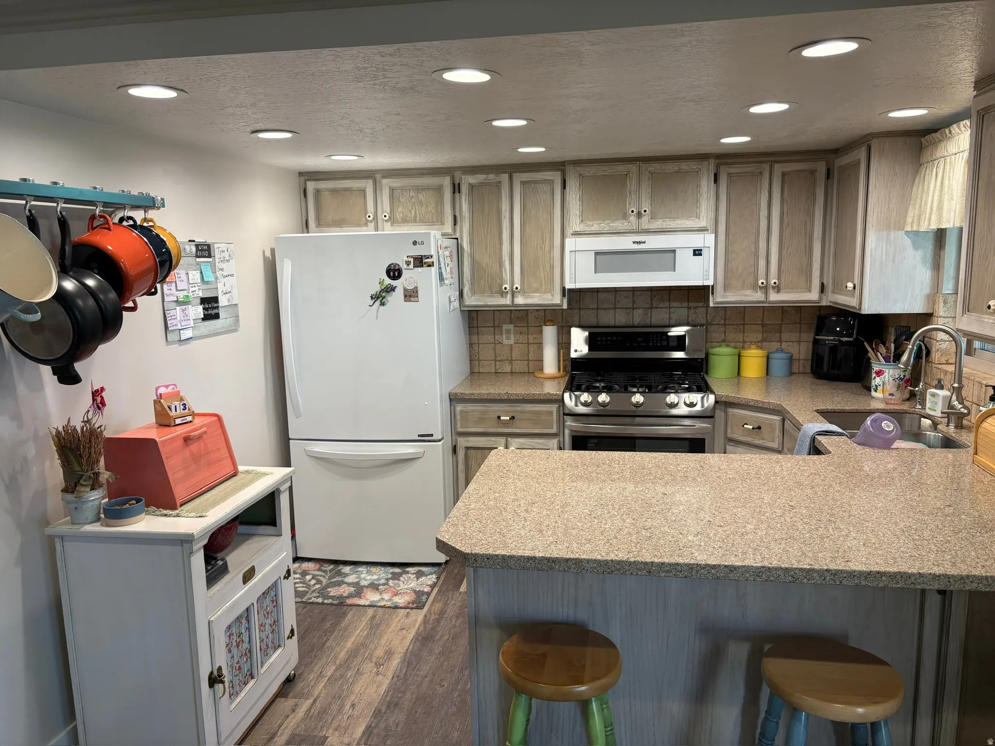Open kitchen with recessed lighting, integrated stainless steel range and microwave, ample cabinetry, L-shaped countertop, and wood-finish flooring