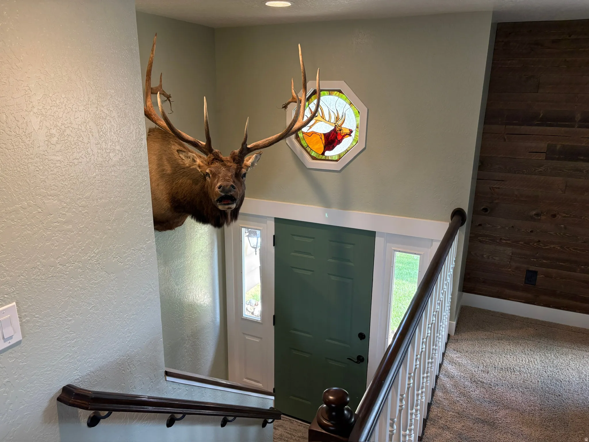 Entryway featuring a green paneled door with sidelights, a stained glass octagonal window, and a wood-paneled accent wall