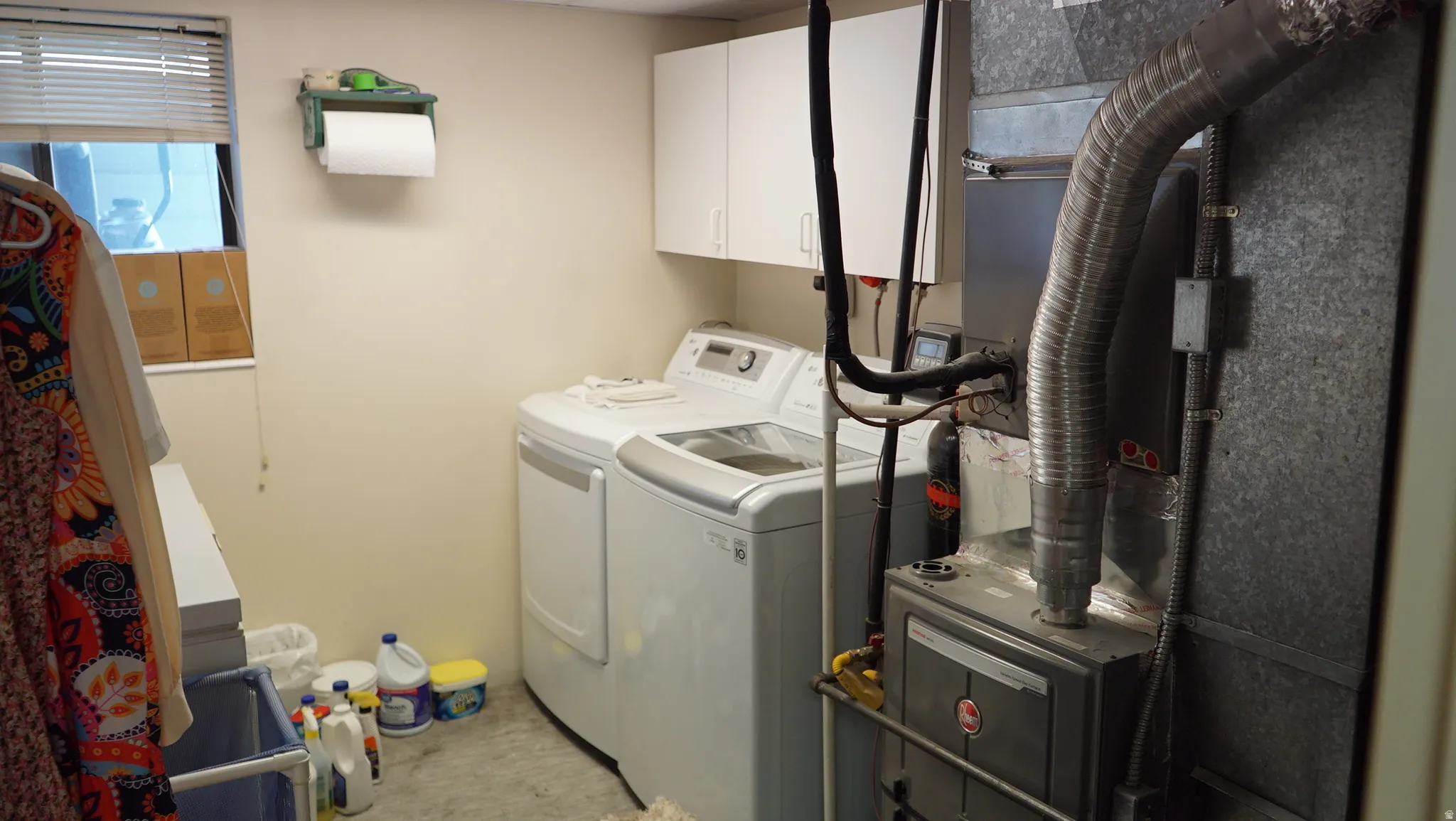 Dedicated utility room featuring a window, built-in upper cabinetry, and a robust furnace unit