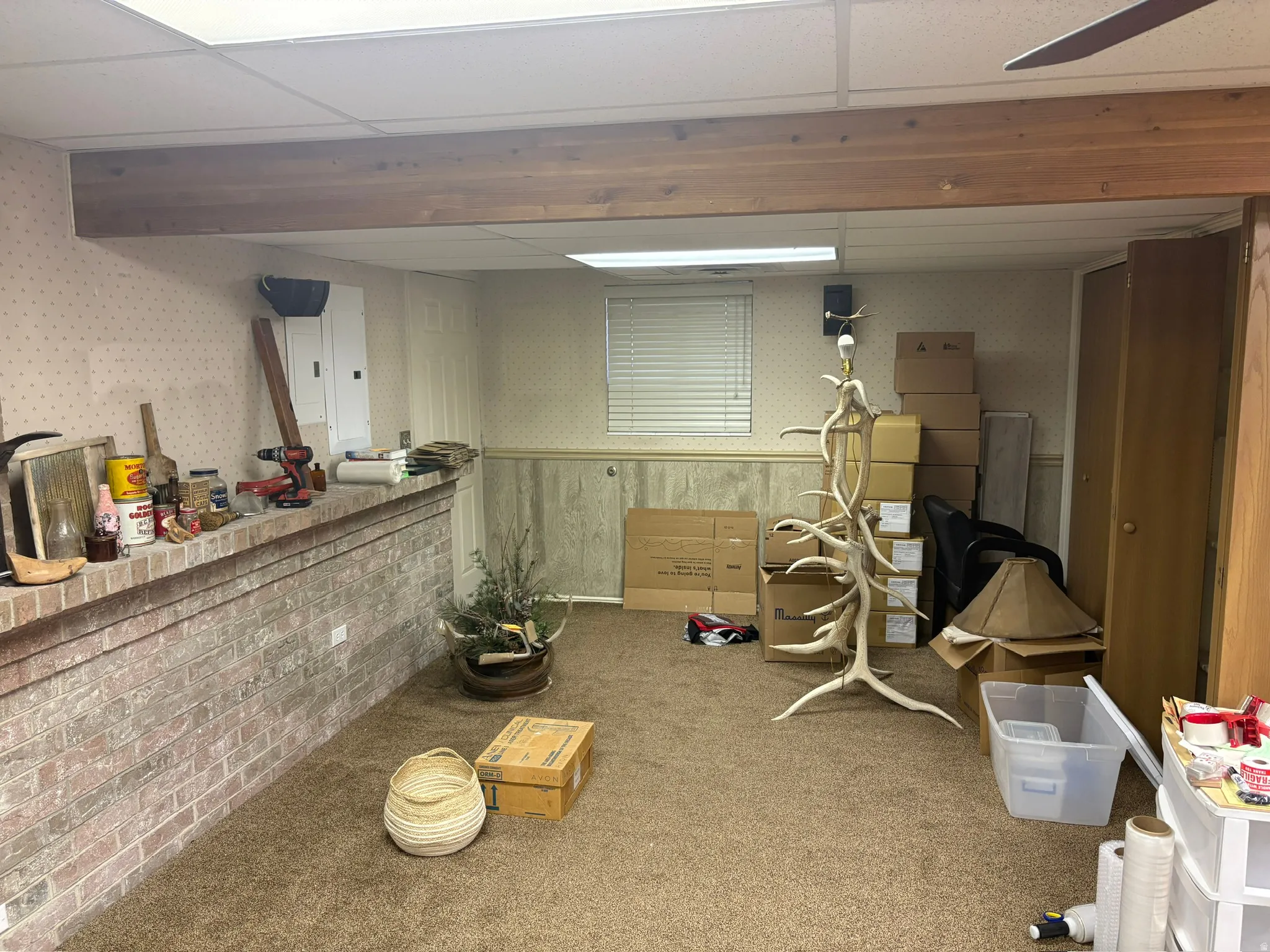 Finished basement area featuring a textured carpet flooring, a drop ceiling with recessed lighting, and exposed wooden beams