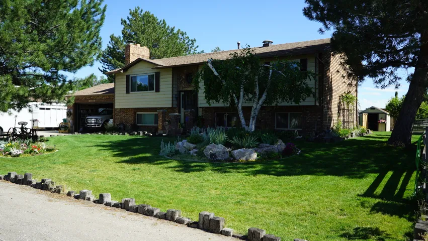 Split-level home featuring a brick and siding exterior, an attached garage, and a lush front lawn with established trees
