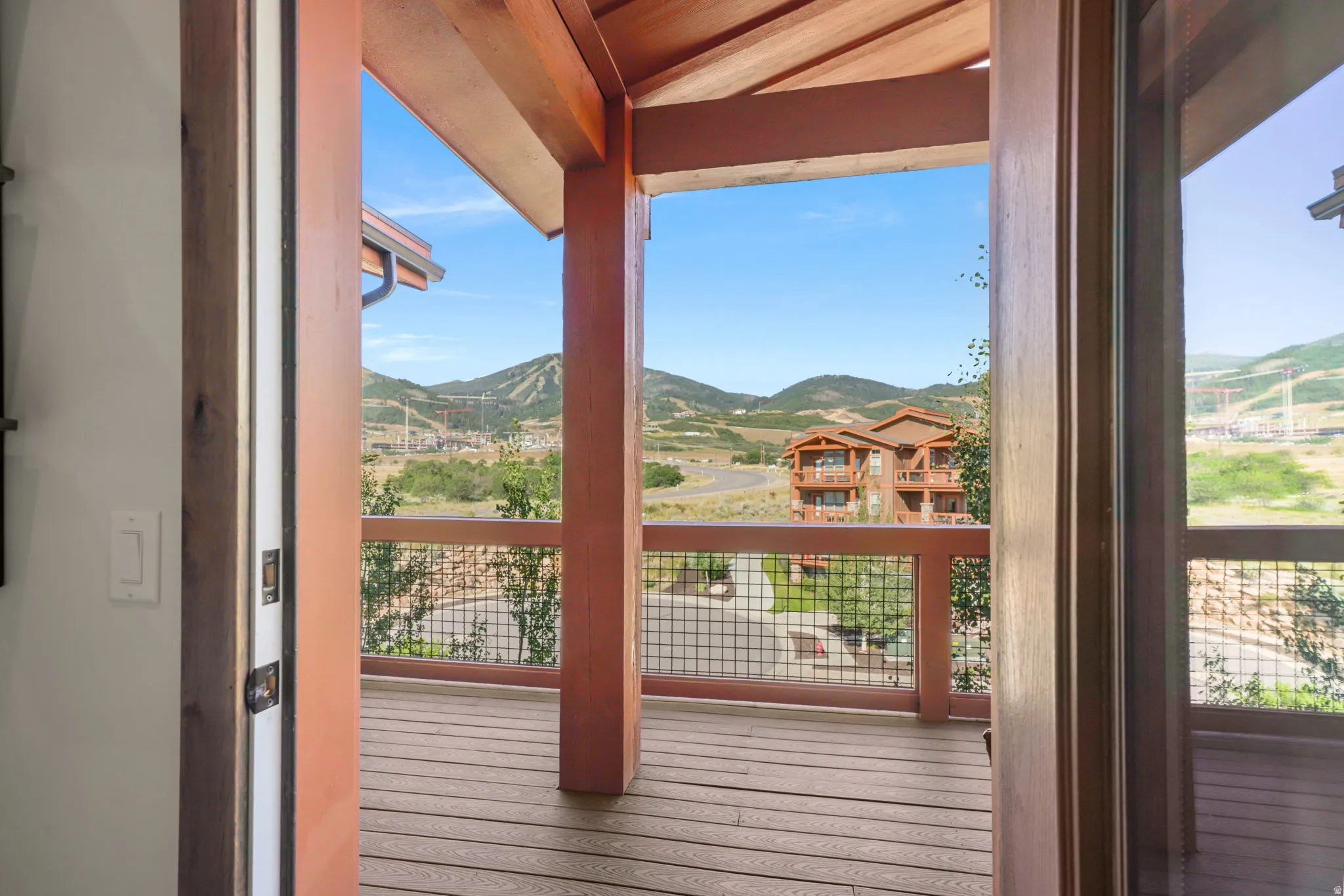 Spacious outdoor deck featuring wood-finish flooring, sturdy wood pillars, and a metal grid railing