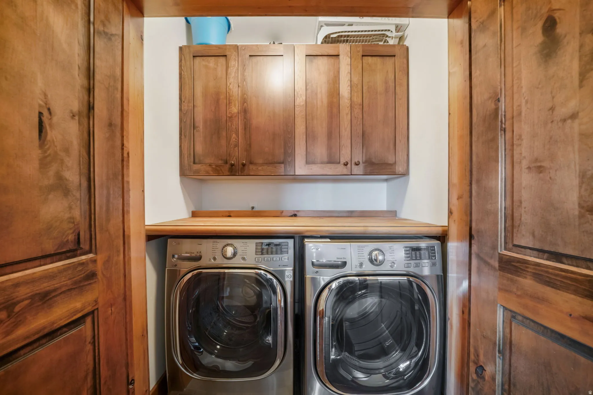 Dedicated laundry area featuring wood-finish cabinetry and a coordinating wood-finish countertop