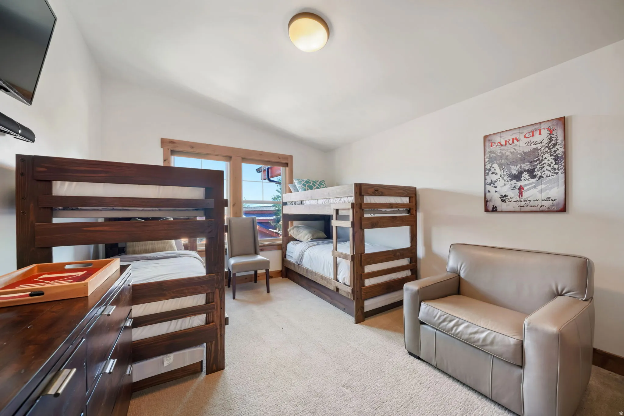 Room featuring two bunk beds with wood frames, light beige carpeting, and a window with wood trim