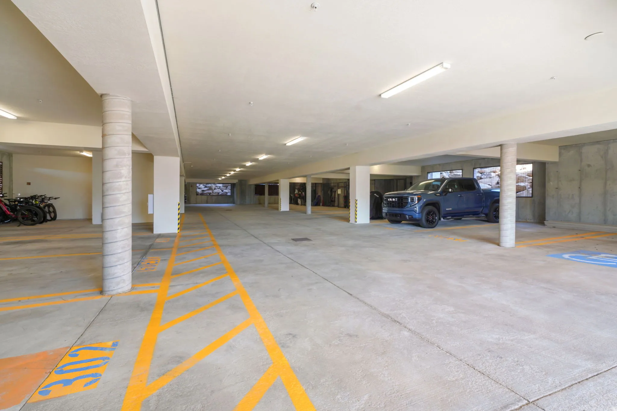 Spacious concrete parking garage with designated parking lines and overhead fluorescent lighting