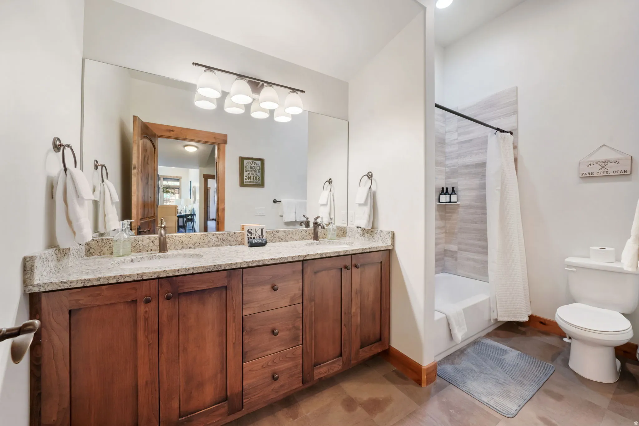 Bathroom featuring a dual sink vanity with granite countertop and wood-finish cabinetry