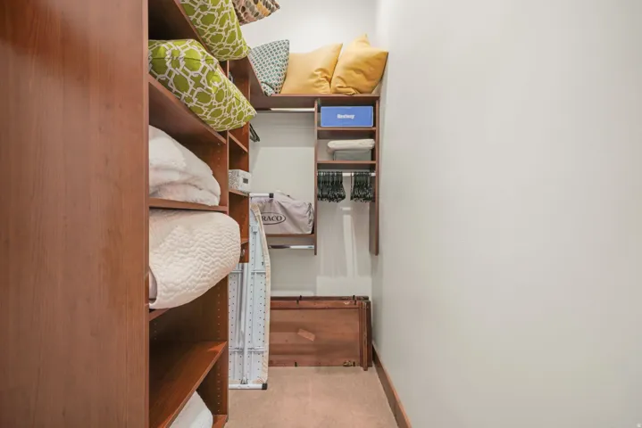 Custom closet system featuring wood-finish shelving, built-in organizers, and a carpeted floor