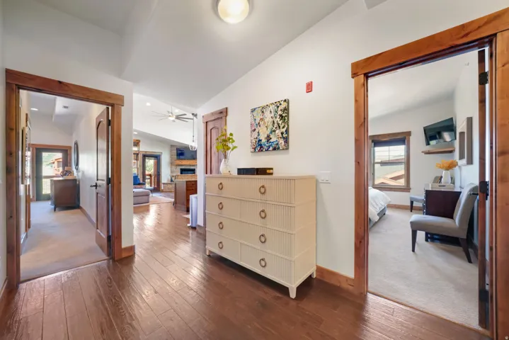 Hallway featuring wood-finish flooring, white walls, and wood trim around doorways