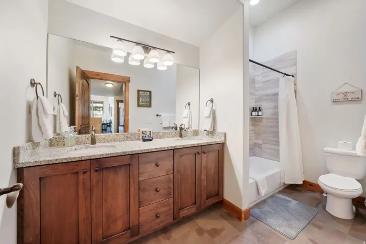 Bathroom featuring a dual sink vanity with granite countertop and wood-finish cabinetry