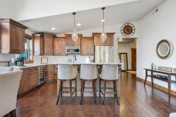 Kitchen featuring wood cabinetry, stainless steel appliances, a built-in wine cooler, and a center island with pendant lighting