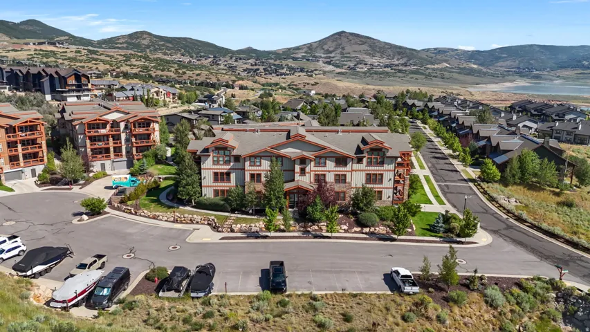 Multi-story residential building featuring a stone and siding exterior, multiple balconies, and a gabled roofline
