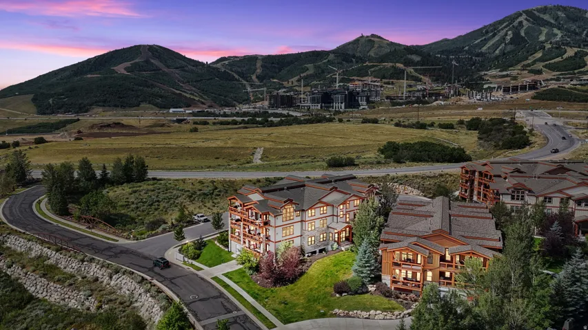 Multi-story residences featuring balconies, textured siding, and pitched roofs, surrounded by landscaped grounds