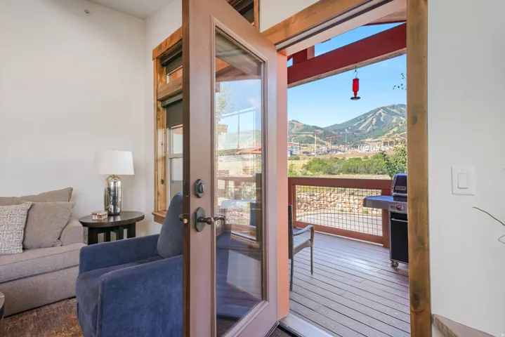 Glass-paneled door opening to a private deck with mountain scenery
