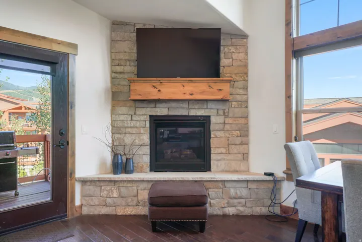 Corner stone fireplace with a natural wood mantel, featuring a built-in media space