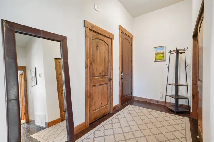 Hallway featuring rich wood-finish doors with arched paneling, coordinating wood baseboards, and dark flooring