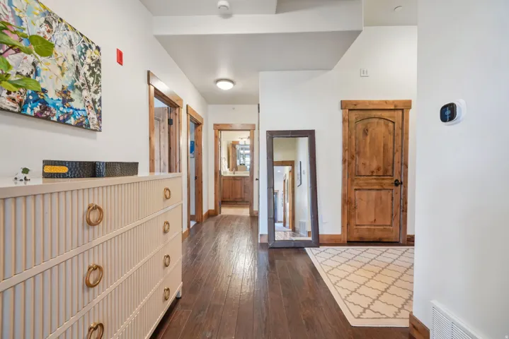 Hardwood-finish flooring extending through a hallway with natural wood doors and trim