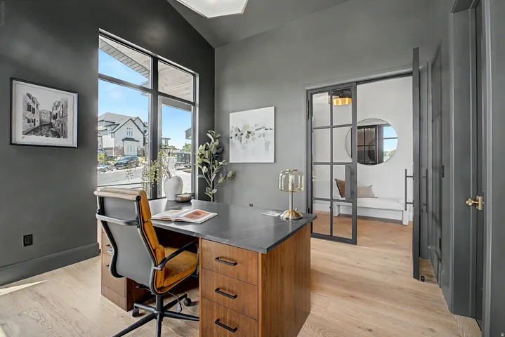 Vaulted ceiling office space featuring wood-finish flooring and a large picture window