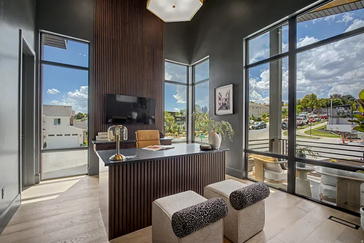 Spacious room with floor-to-ceiling windows, wood-finish flooring, and a modern desk with a dark countertop