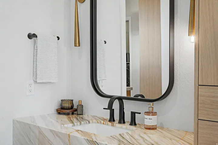 Modern bathroom featuring a rectangular under-mount sink set into a veined stone countertop