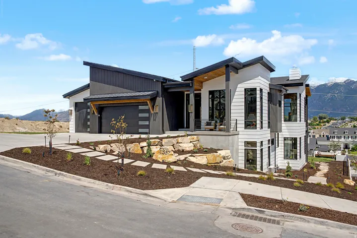 Modern architectural exterior featuring contrasting dark and light siding, multiple large windows, and a multi-level design
