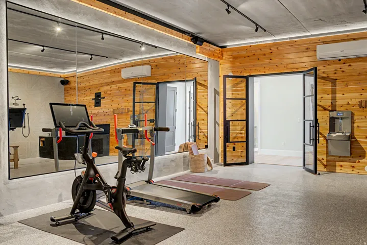 Dedicated fitness space featuring a full-wall mirror, wood-finish accent wall, and concrete flooring