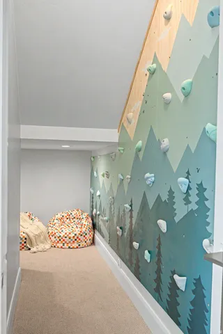 Indoor climbing wall featuring a custom painted mural and integrated climbing holds