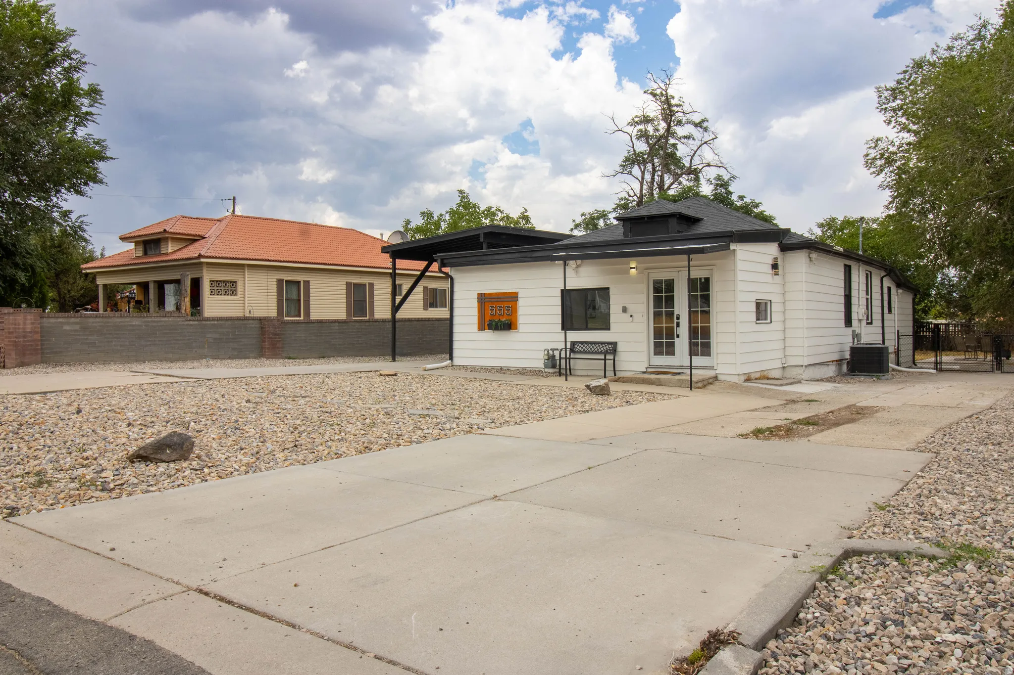 Front of home, featuring xeriscape front yard, and driveway to back with gated fencing driveway, and gravel landscaping