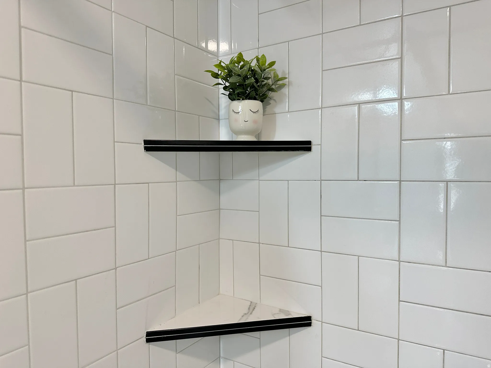 White rectangular wall tiles with a varying pattern, complemented by two built-in corner shelves