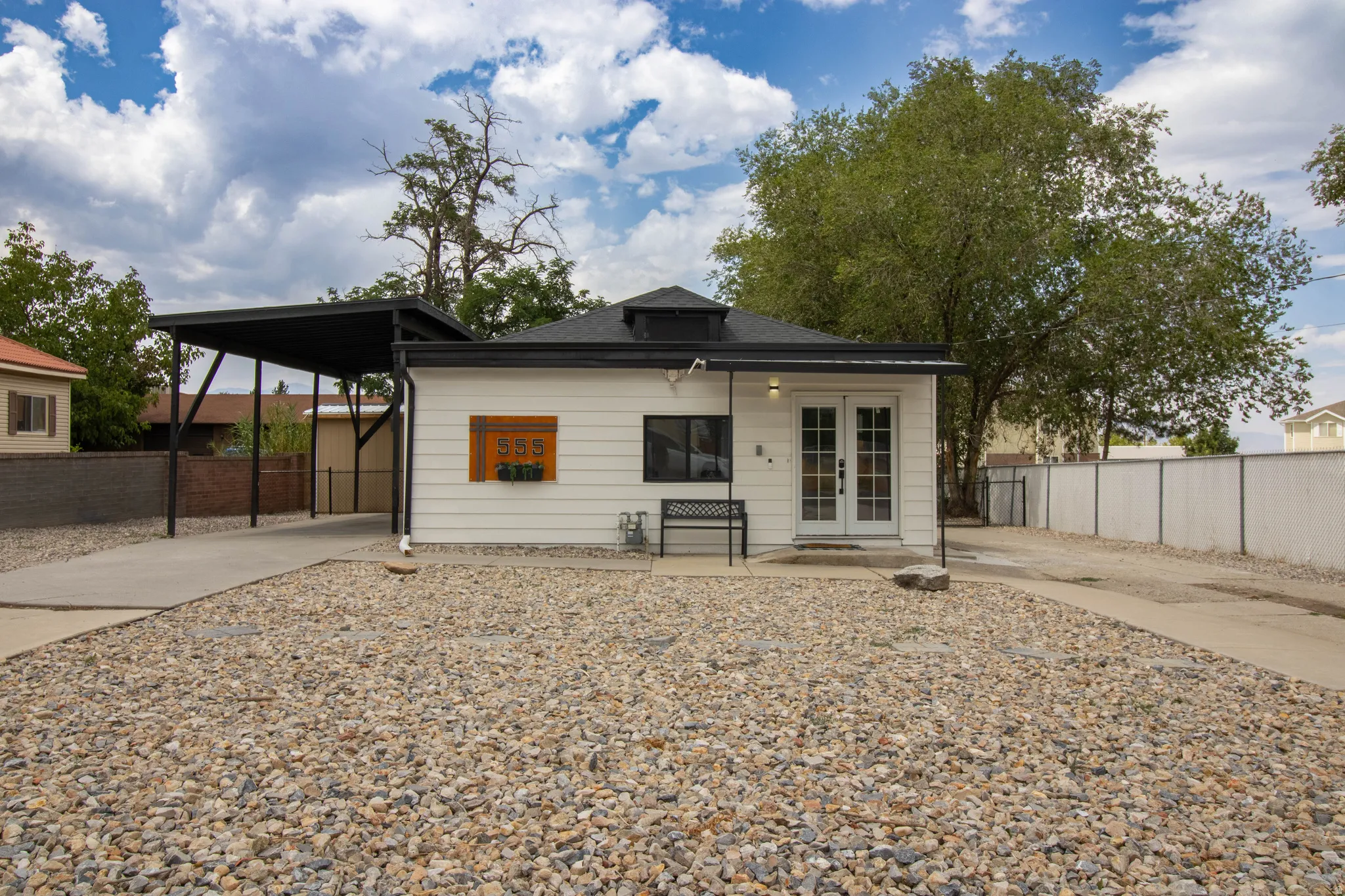 Front of home, with two driveways, large covered carport, and xeriscape front yard