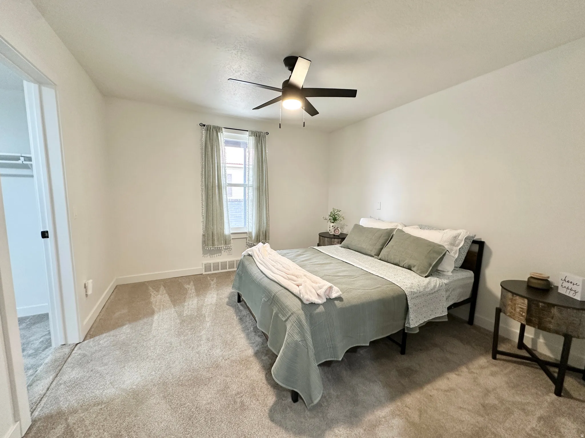 Primary bedroom featuring a ceiling fan with integrated lighting, a window and a massive recessed walk-in closet with shelving on 3 walls