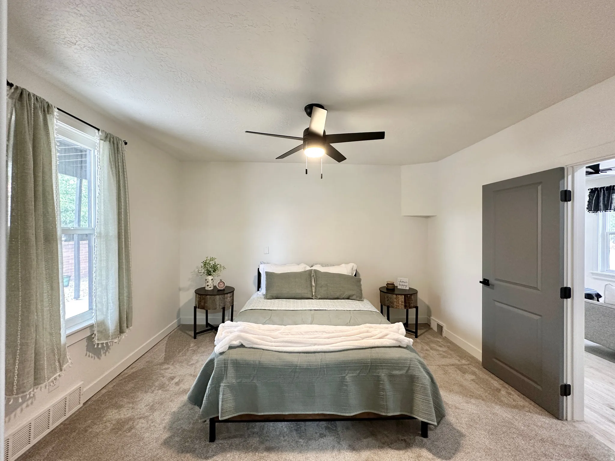 Spacious room featuring neutral carpeting, a ceiling fan with integrated lighting, and a modern paneled door