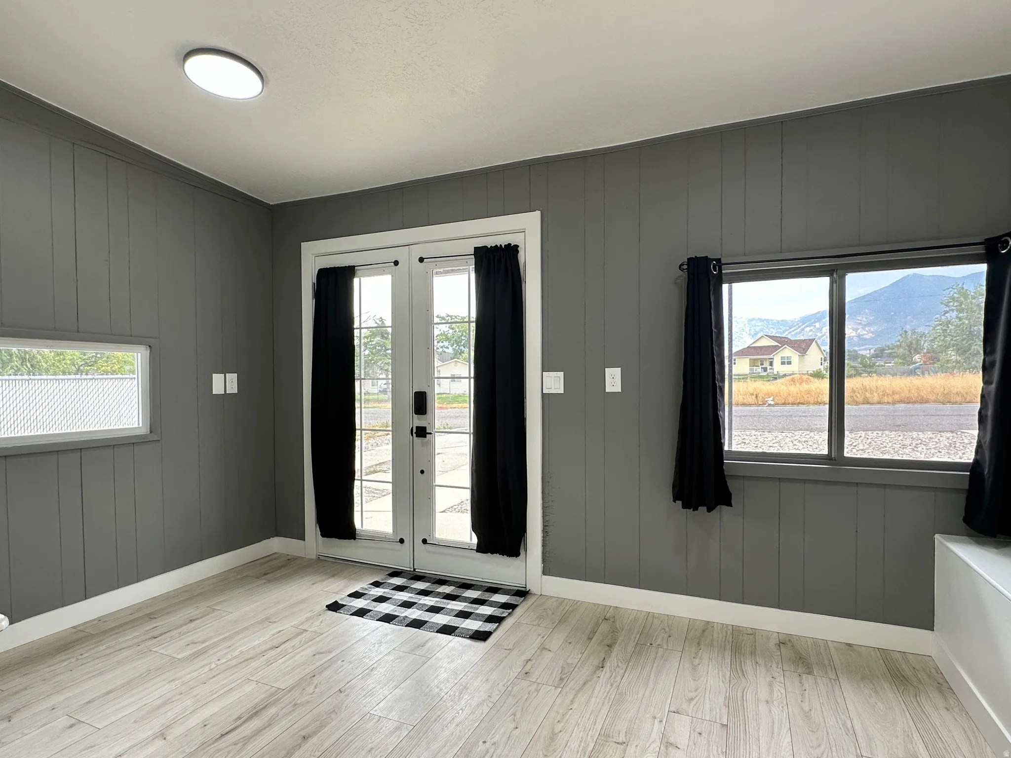 Front foyer featuring board and batten walls, light wood-finish flooring, and a ceiling-mounted light fixture
