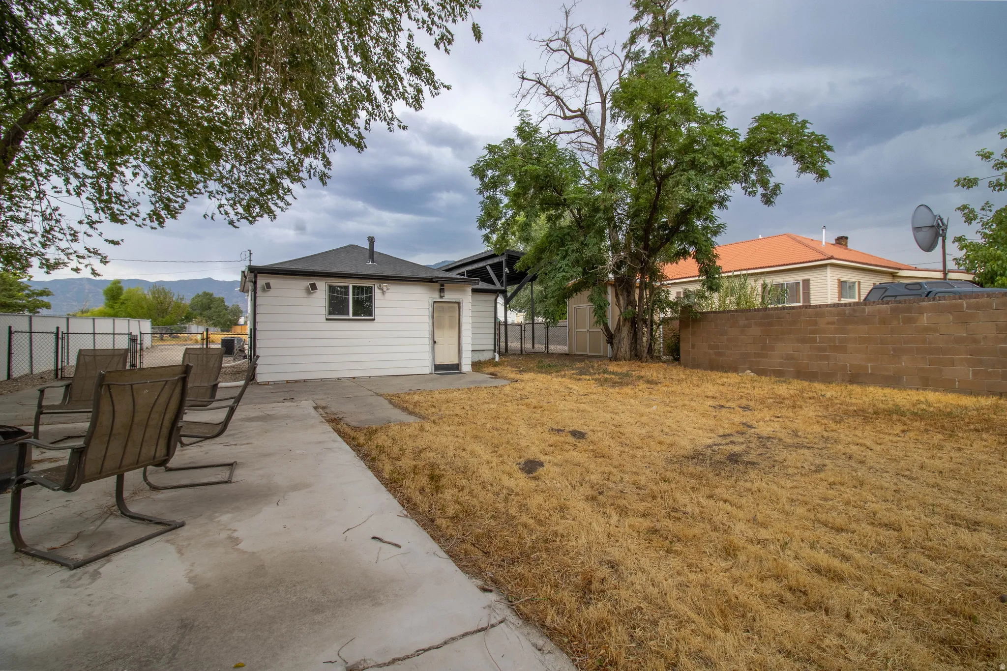 Expansive concrete patio area with a white exterior structure and a concrete block privacy wall