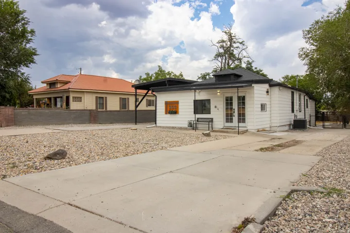 Front of home, featuring xeriscape front yard, and driveway to back with gated fencing driveway, and gravel landscaping