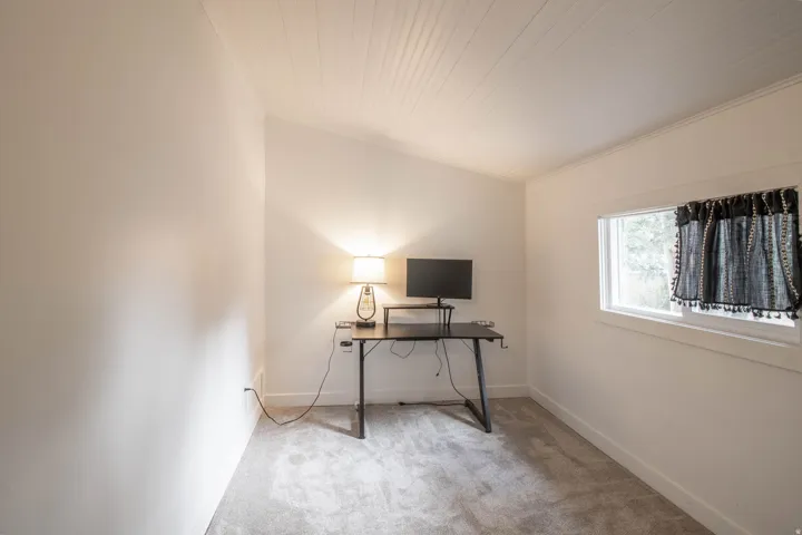 Vaulted ceiling with light-colored carpet flooring
