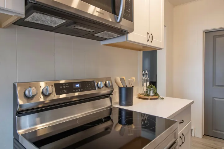 Stainless steel electric range with a smooth cooktop, complemented by a matching built-in microwave and vent hood