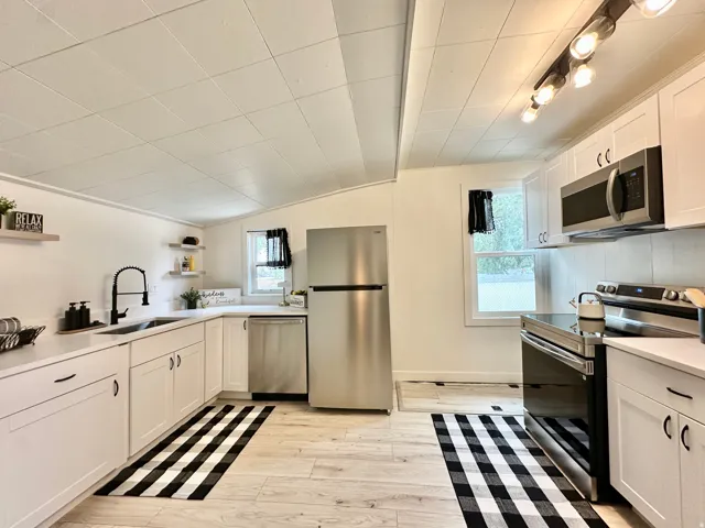 Modern kitchen featuring white cabinetry, light-toned wood-finish flooring, and white quartz countertops