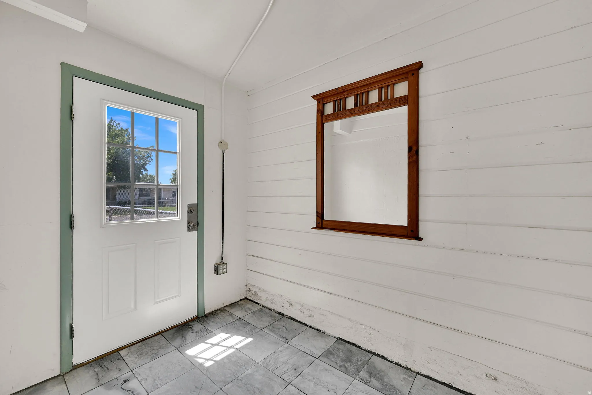 White paneled door with a grid window, framed by green trim
