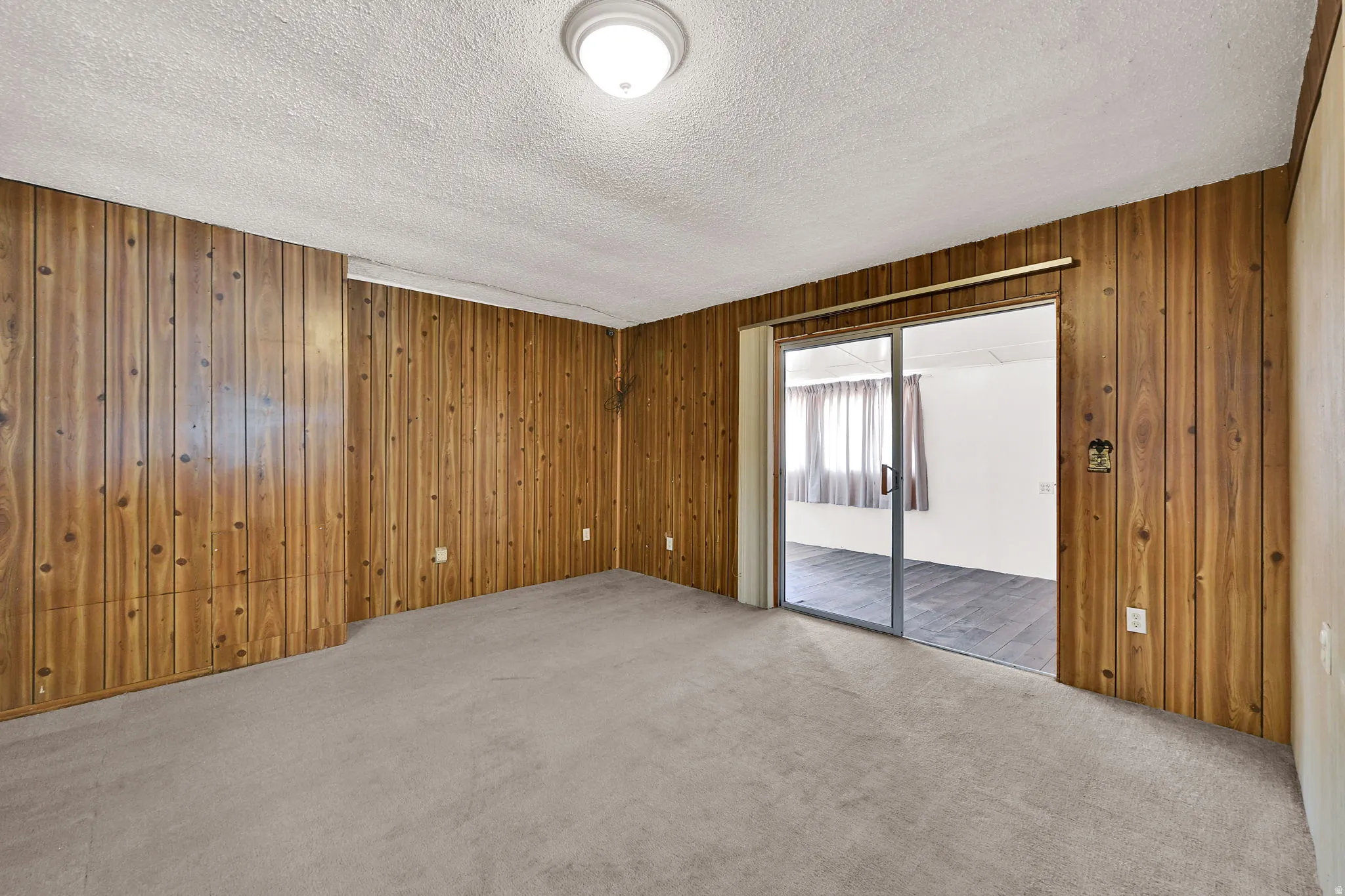 Room featuring wood paneling on multiple walls and light-colored carpet flooring