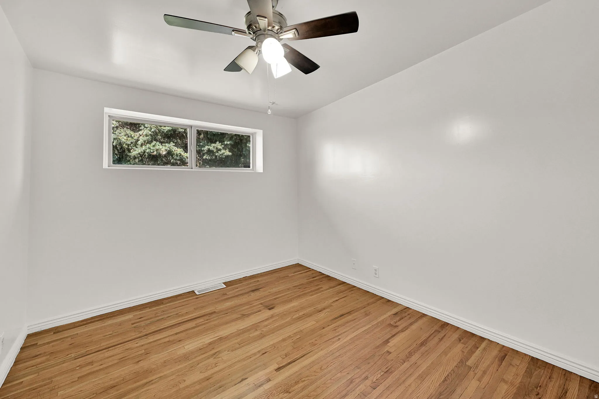 Room featuring wood-finish flooring, white walls, and a multi-pane window