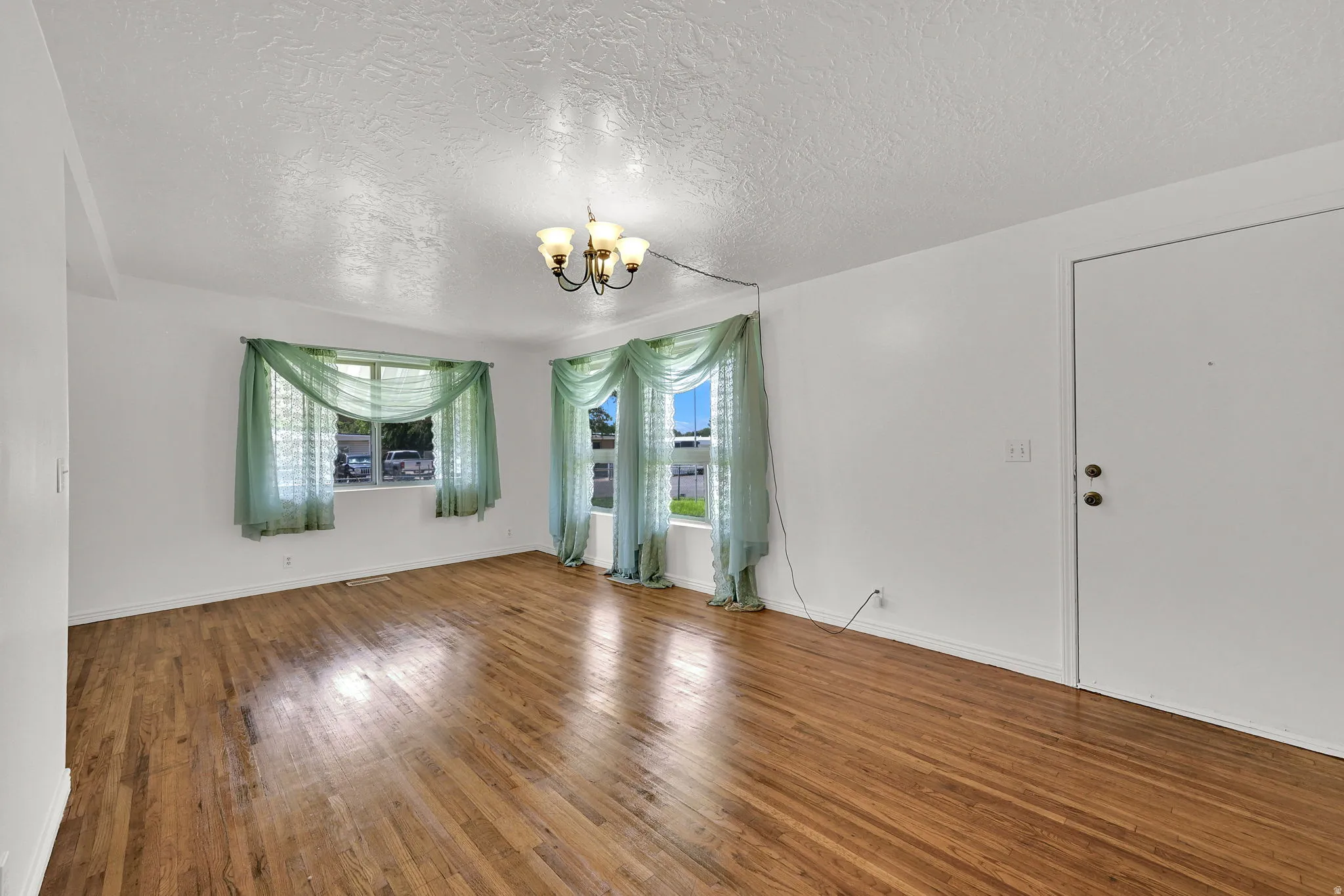 Bright interior space featuring wood-finish flooring, white walls, and two windows