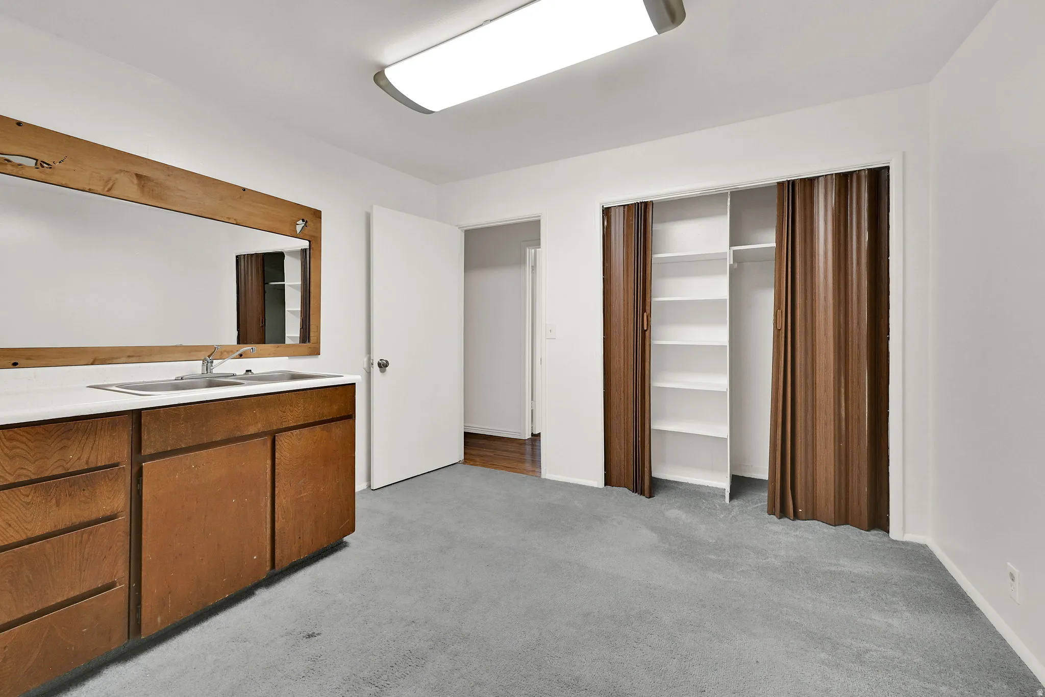 Interior space featuring a built-in vanity with a rectangular sink, wood-finish cabinetry, and a large framed mirror