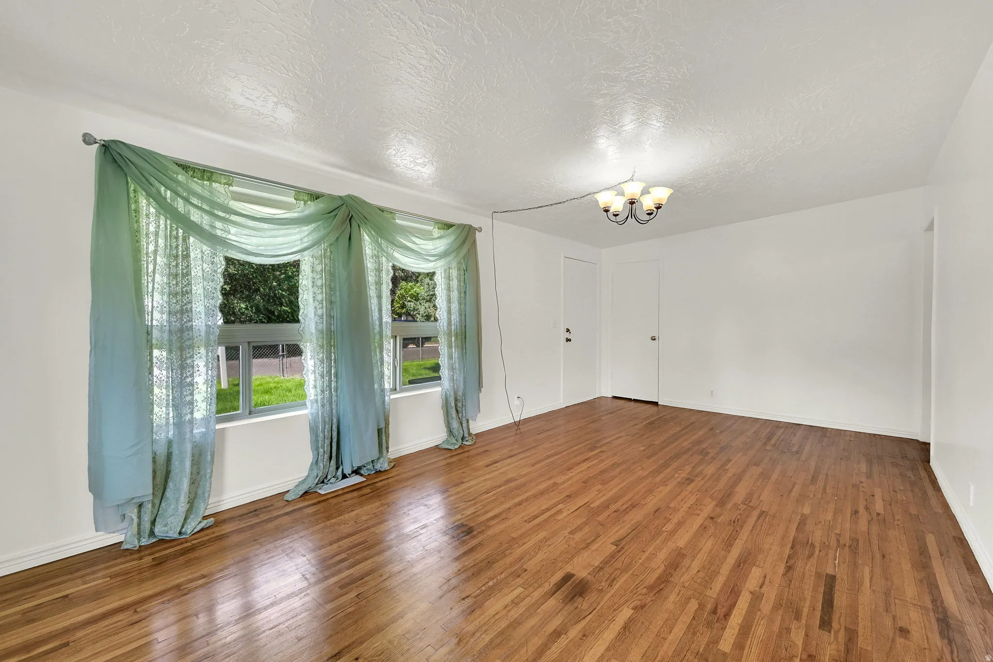 Spacious interior featuring wood-finish flooring, white walls, and a multi-pane window