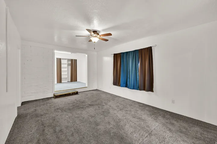 Living area featuring neutral wall tones, textured ceiling, and a ceiling fan with integrated lighting