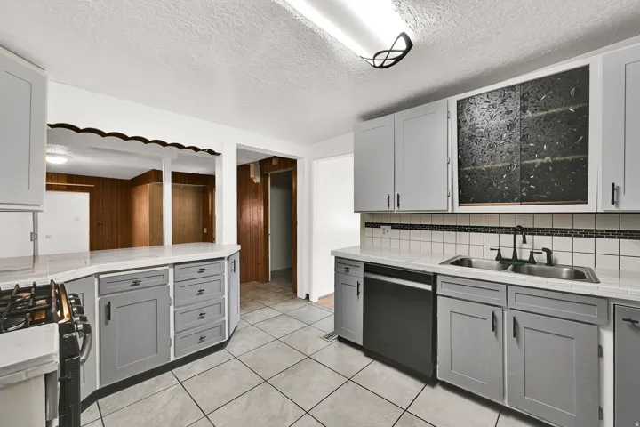 Kitchen featuring light gray cabinetry, light countertops, and a white square tile backsplash with a dark accent border